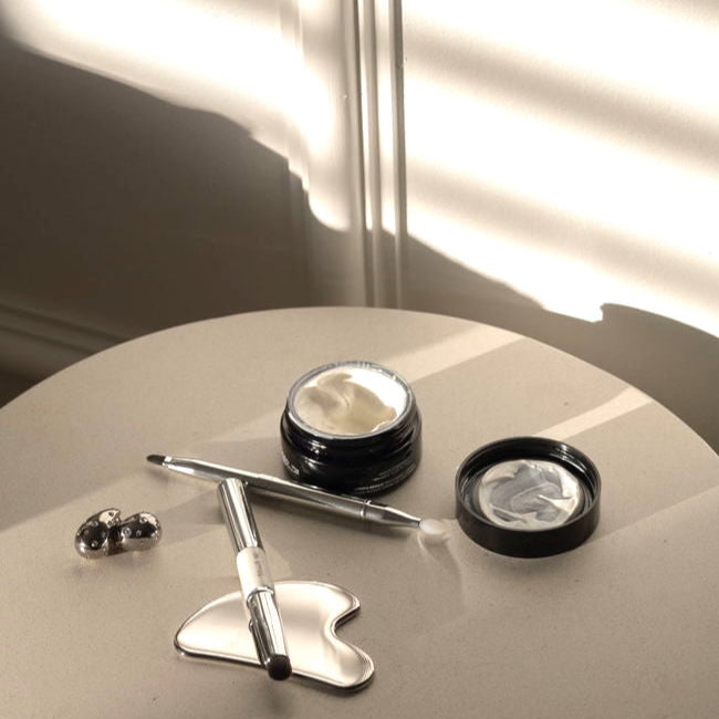 Gua Sha facial tool for sculpting, lymphatic drainage, and reducing puffiness, placed on a table with skincare items.