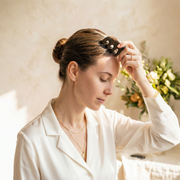 Woman using a wooden scalp massage comb as part of a daily wellness ritual at home